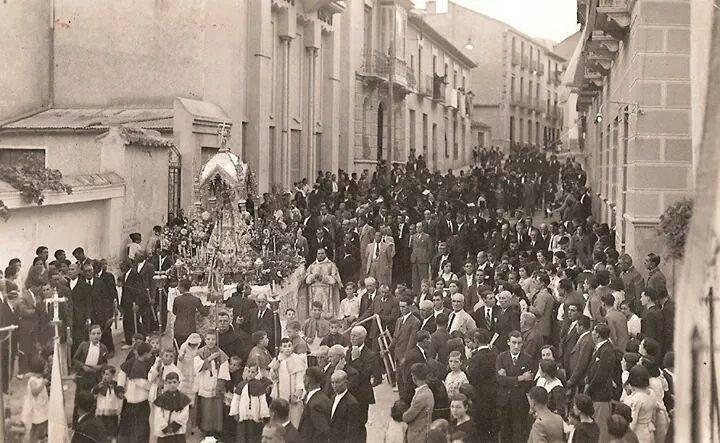 Procesión de la Virgen de la Piedad posiblemente en el día 14 de septiembre después. la fotografía es del archivo histórico de Estudios fotográficos Caparrós. En ella aparece Marcos Caparrós Torres con traje de chaqueta claro y corbata oscura, tras él, aparece José Caparrós Torres. La calle Alhamillos repleta.